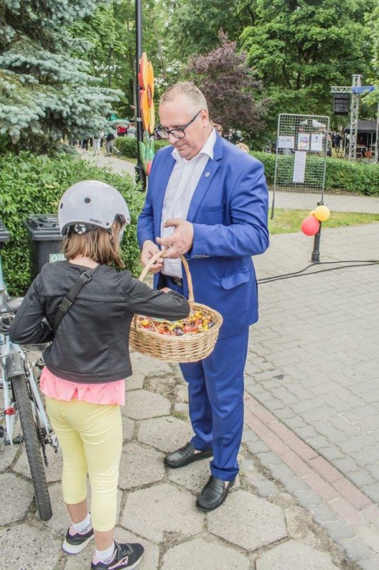 burmistrz częstuje cukierkami dziewczynkę