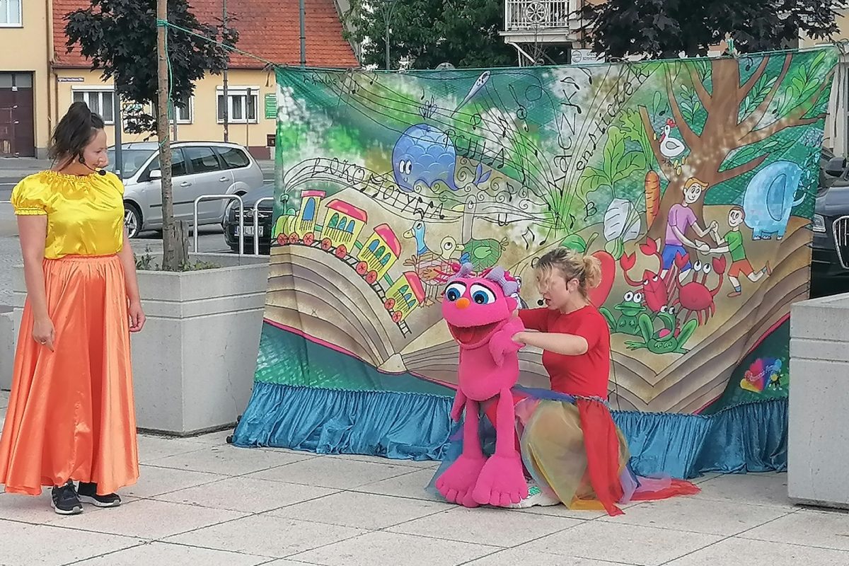 Aktorki na tle dekoracji teatralnej z pluszowym zabawnym ludzikiem