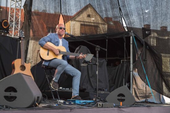 Artysta z gitarą na scenie.