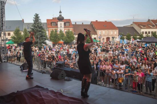 Artyści na scenie, tłum publiczności przed sceną.