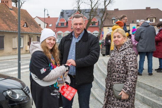 Osoby wrzucające pieniądze do puszki wolontariusza