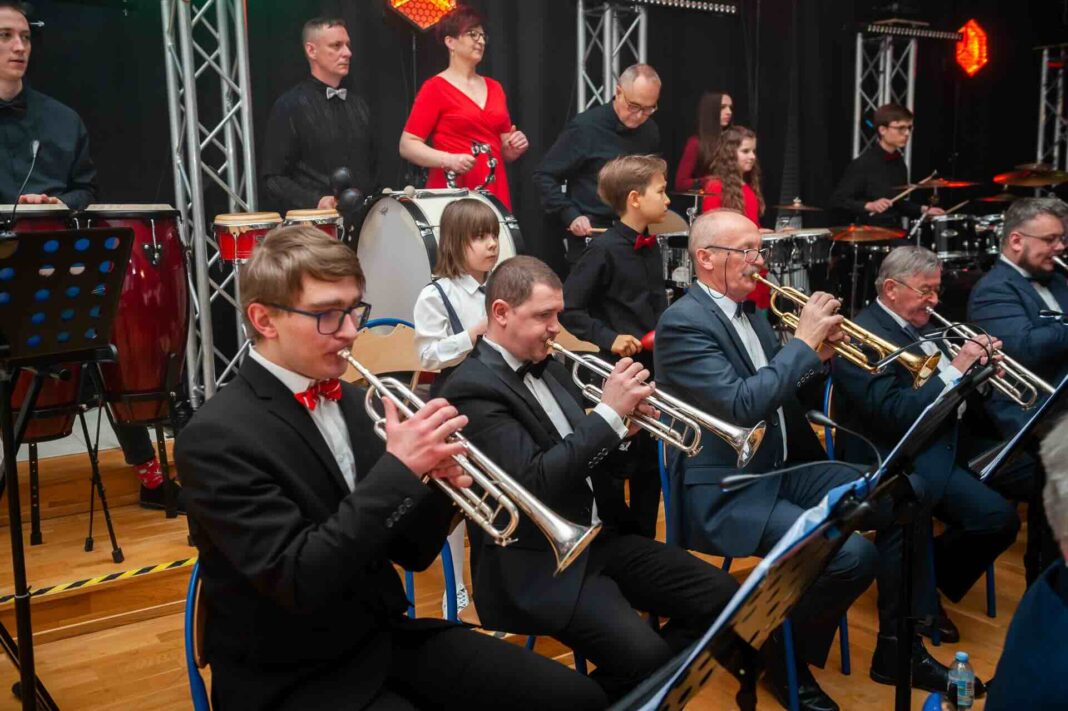 Ludzie grają na trąbkach, w tle sekcja perkusji