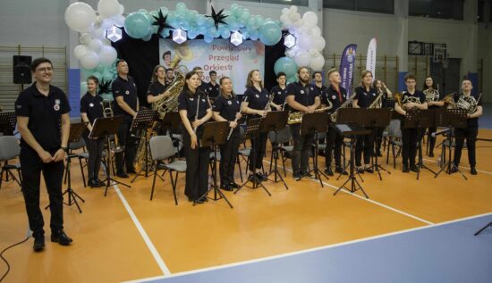 Muzycy orkiestry dętej wraz z dyrygentem na hali widowiskowo-sportowej