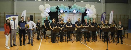 Zdjęcie grupowe orkiestry i dyrygenta wraz z przedstawicielami organizatora