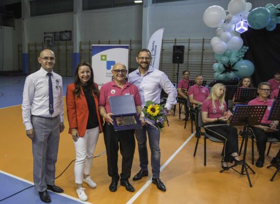 Zdjęcie grupowe orkiestry dętej wraz z dyrygentem i przedstawicielami organizatora