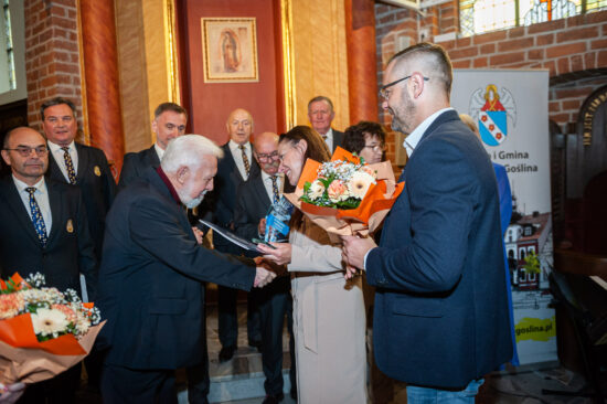 kobieta i mężczyzna wręczają kwiaty mężczyźnie