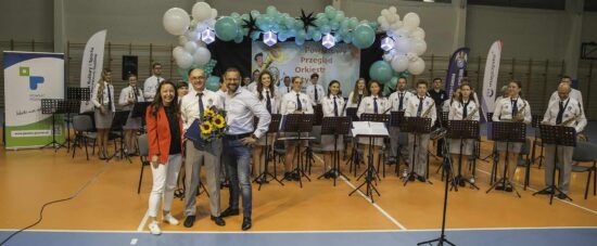 Zdjęcie grupowe orkiestry i dyrygenta wraz z przedstawicielami organizatora