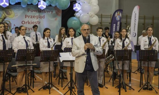 Mężczyzna z mikrofonem w tle orkiestra dęta