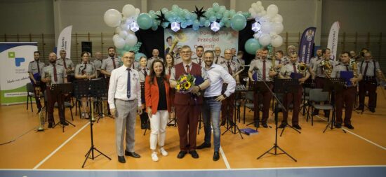 Zdjęcie grupowe orkiestry dętej wraz z dyrygentem i przedstawicielami organizatora