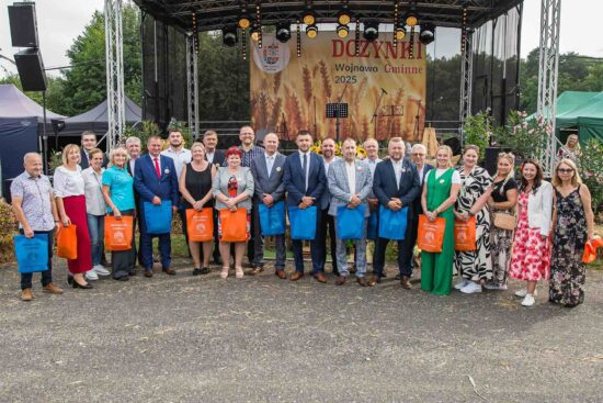 Zdjęcie grupowe, sołtysi pozują do zdjęcia pod sceną.