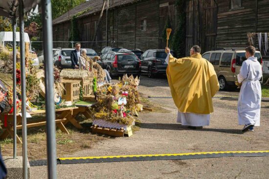 Ksiądz święci wieńce dożynkowe.
