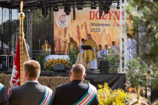 Księża i ministranci na scenie podczas mszy polowej.