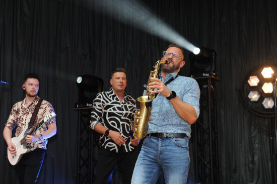 Zespół na scenie oraz artysta grający na saksofonie