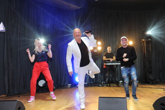 Artysta na scenie w towarzystwie kobiety i mężczyzn