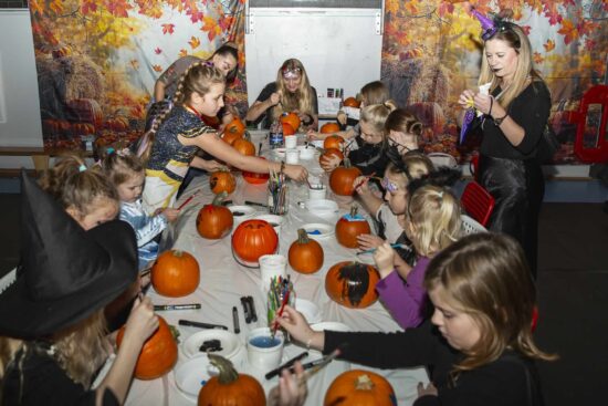 Dzieci przy stole malujące dynie