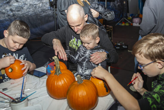 Dzieci i dorośli przy stole malujące dynie