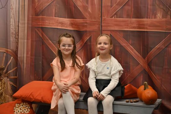 Dwie dziewczynki siedzą na ławce na tle jesiennej scenografii