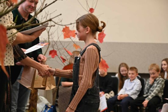 Dziewczynka przyjmuje gratulacje od jury w tle publiczność