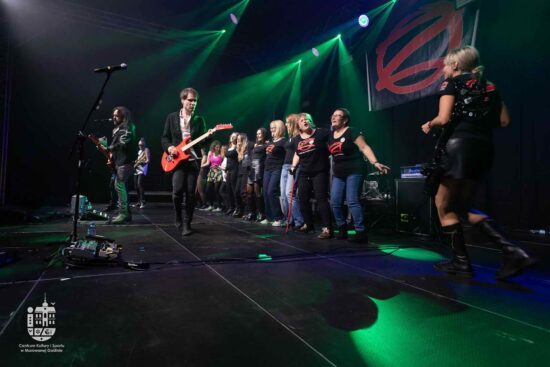 Zespół gra na scenie oraz tańczące panie