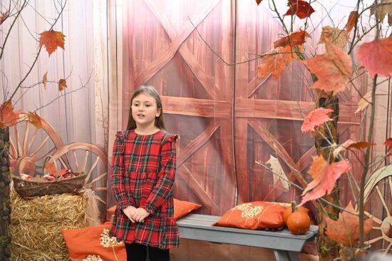 Dziewczynka recytująca  wiersz na tle jesiennej scenografii