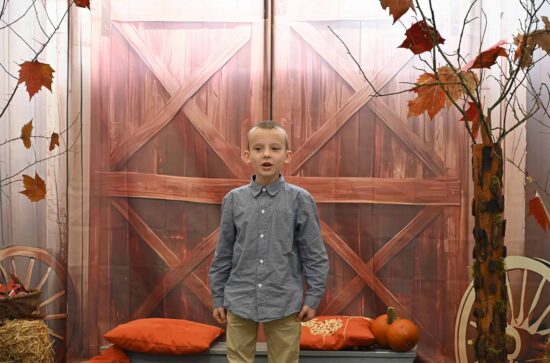 Recytujący chłopiec w koszuli na tle jesiennej scenografii 