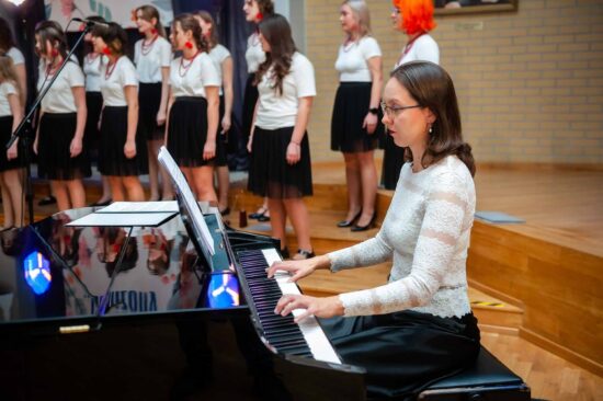 Akompaniatorka gra na fortepianie w tle chór.