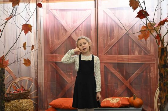 Dziewczynka recytująca na tle jesiennej scenografii