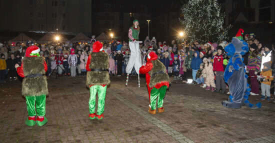 Aktorzy , szczudlarka i gigantyczna maskotka kot zabawiają publiczność