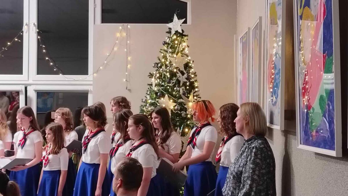 Chórzystki stojące przy choince z dyrygentką