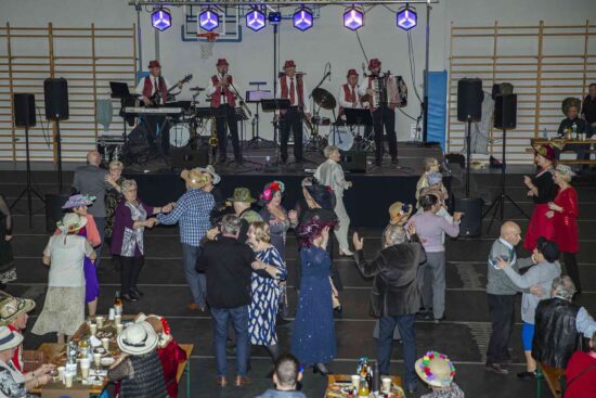 Sala z  seniorami siedzącymi przy stolikach