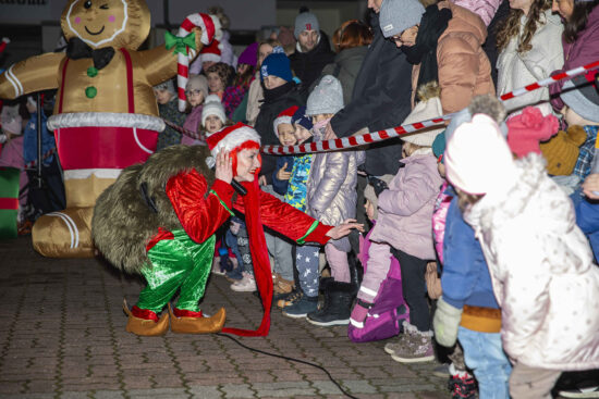 Aktorka przebrana za elfa kuca przy dziecku i podaje rękę, w tle publiczność
