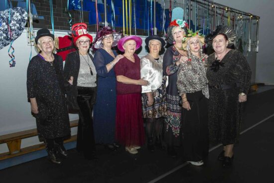 Grupa kobiet w fantazyjnych kapeluszach pozuje do zdjęcia