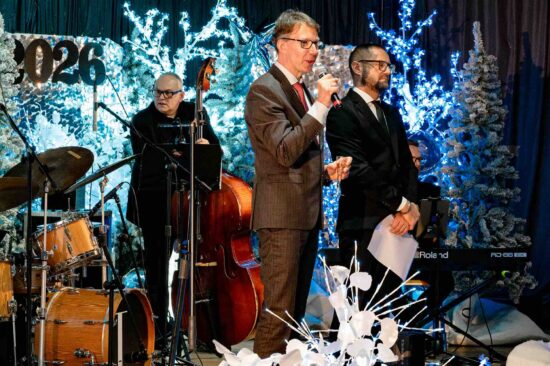 dwóch mężczyzn na scenie wita publiczność, w tle mężczyzna przy kontrabasie