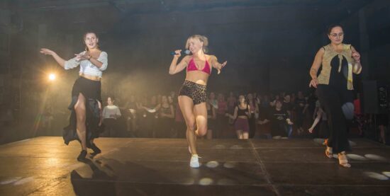 Na pierwszym planie tańczące 3 kobiety, w tle uczestnicy maratonu