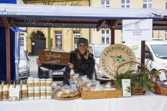 kobieta przy stoisku trzyma napis Wesołych Świąt