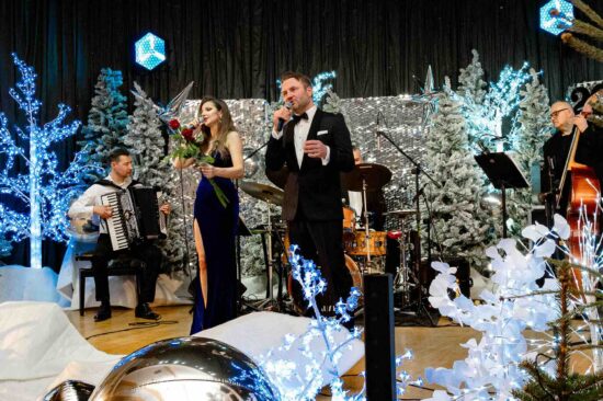 mężczyzna i kobieta śpiewają na scenie, kobieta trzyma dwie róże