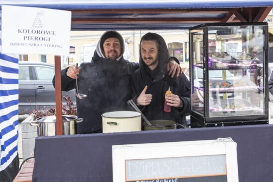 dwóch mężczyzn przy stoisku z kolorowymi pierogami