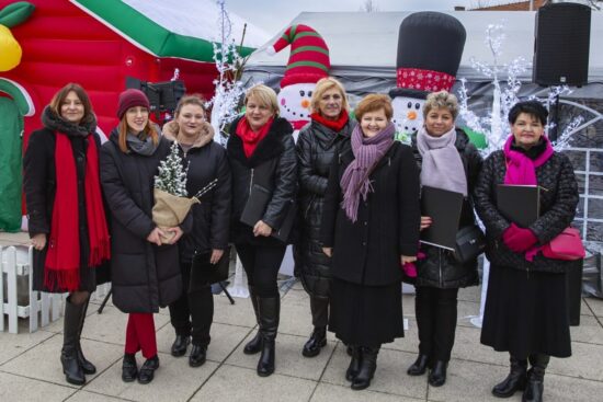 grupa kobiet pozuje do zdjęcia na tle świątecznej dekoracji