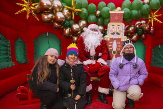 trzy dziewczynki pozują do zdjęcia ze św. Mikołajem