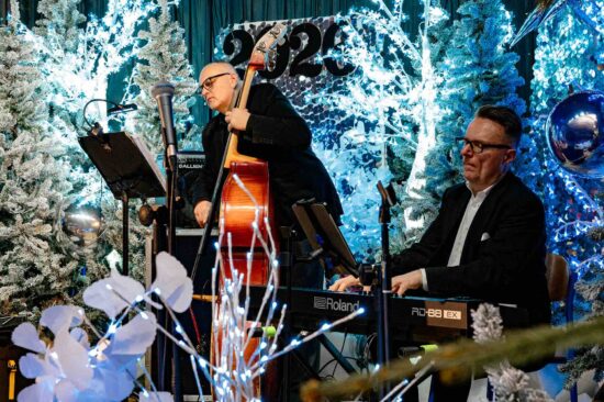 dwóch muzyków na scenie: mężczyzna gra na instrumencie klawiszowym, obok kontrabasista