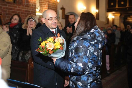 kobieta przekazuje kwiaty dyrygentowi