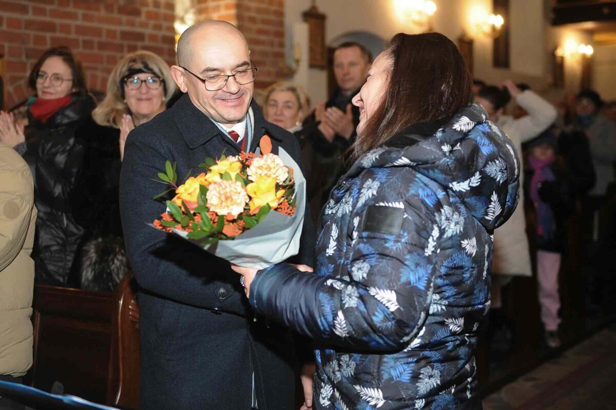 kobieta przekazuje kwiaty dyrygentowi