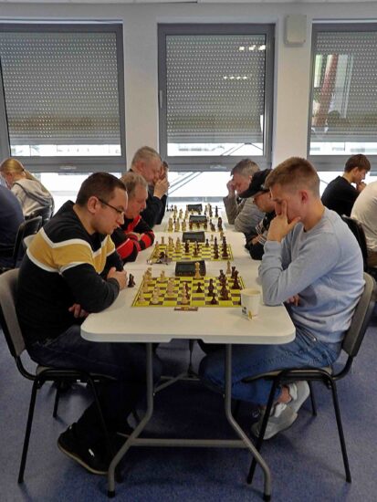 Szachiści przy stołach, szachownice, zegary