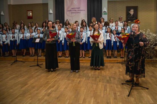 Na pierwszym planie stoją dyrygentki z kwiatami za nimi wszystkie chóry Canzona