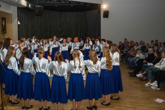 Chór dziewczęcy Canzona -grupa starsza -stojąca w okręgu. W tle publiczność