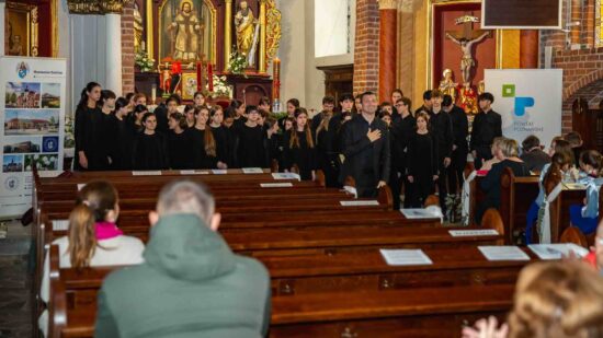 Veus Cor Infantil Amics de la Unióz Granollers z Katalonii z dyrygentem stoją i na tle ołtarza