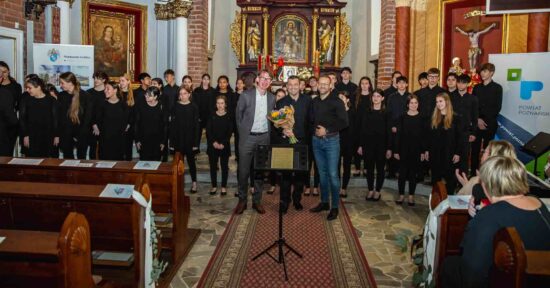Do zdjęcia pozują na tle Veus Cor Infantil Amics de la Unióz Granollers zastępca Burmistrza Marcin Buliński, dyrygent chóru Josep Vila Jover  i Sławomir Heinrychowski -dyrektor CKiS w Murowanej Goślinie