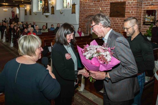 Gratulacje i kwiaty dla Jadwigi Jaskólskiej dyrygentki Chóru Mieszanego Vocantes  składają Marcin Buliński , Sławomir Heinrychowski i Elżbieta Wtorkowska