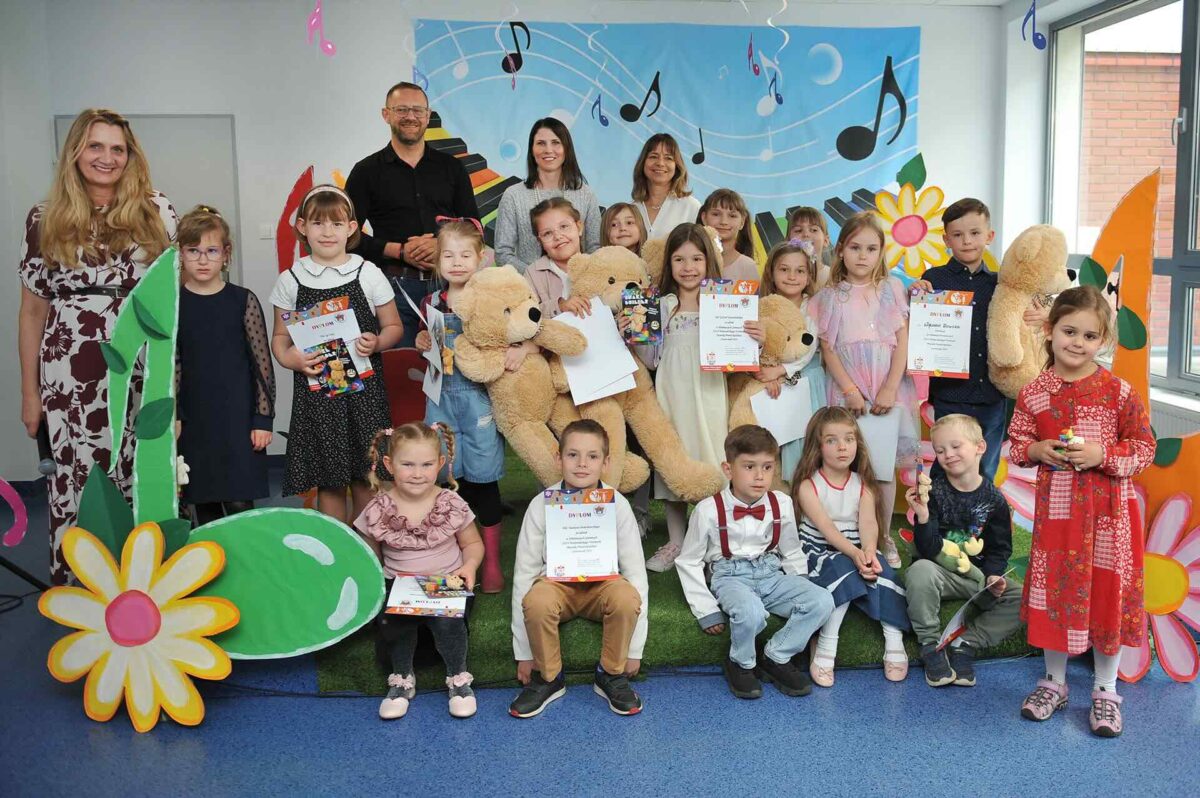 Na tle kolorowej scenografii wszyscy uczestnicy konkursu oraz jury pozują do zdjęcia