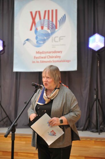 Kobieta z mikrofonem, baner festiwalowy w tle
